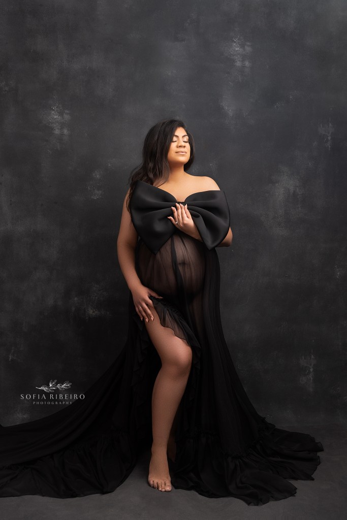 a black bow is draped above moms bump during a maternity portrait
