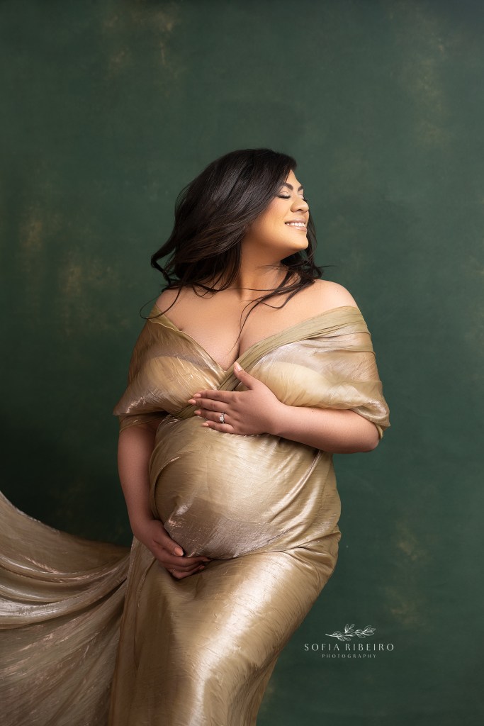 radiant mom glows in a gold gown highlighting her baby bumo