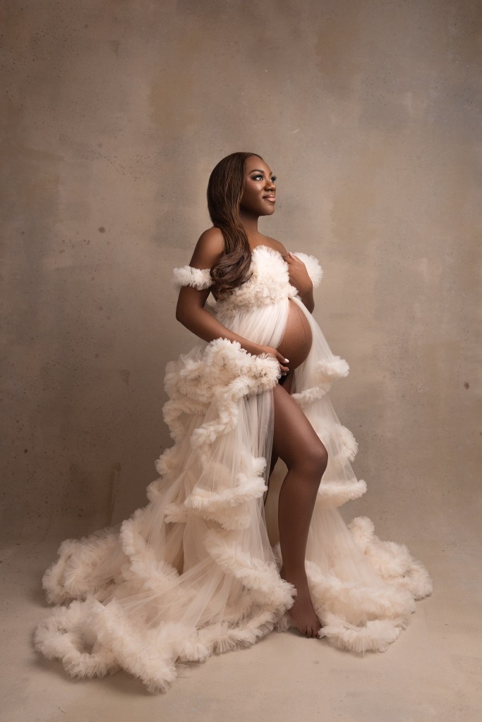 A proud expecting mom stands in a studio in a tule maternity gown before finding baby shower venues union county nj