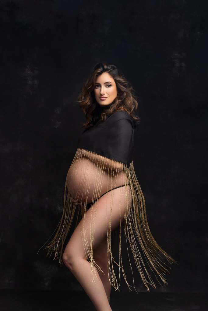 mom poses in a dramatic fringed top highlighting the belly with a nj maternity photography studio