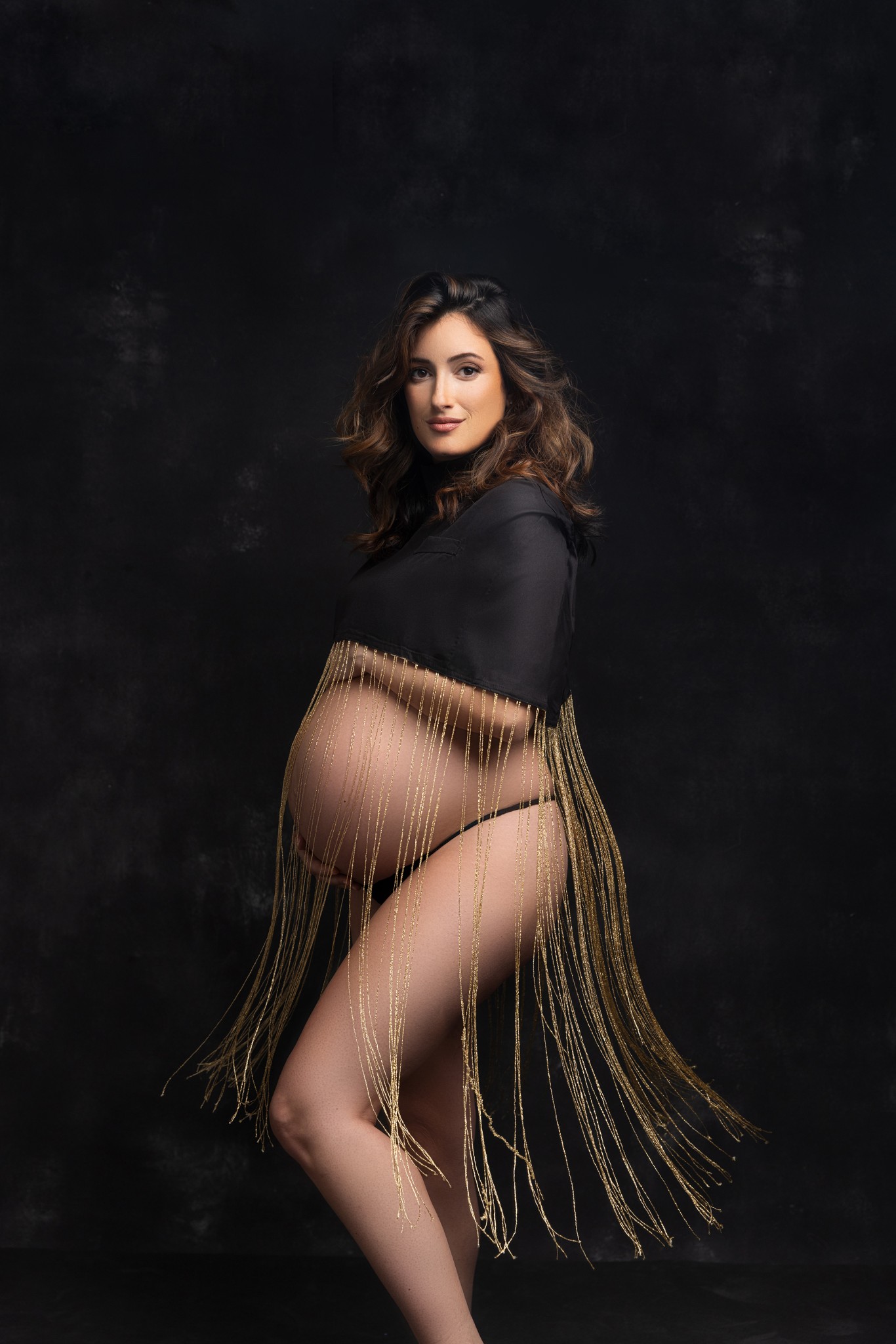 mom poses in a dramatic fringed top highlighting the belly with a nj maternity photography studio
