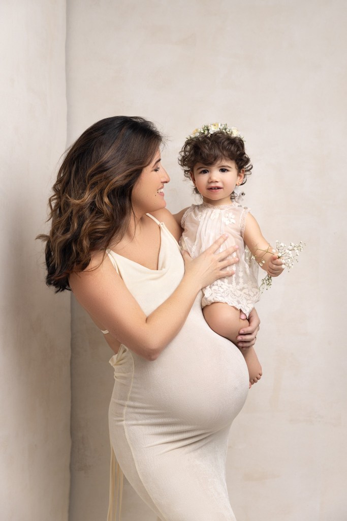 mom and baby girl snuggle her baby bump during a photo session with a nj maternity photographer