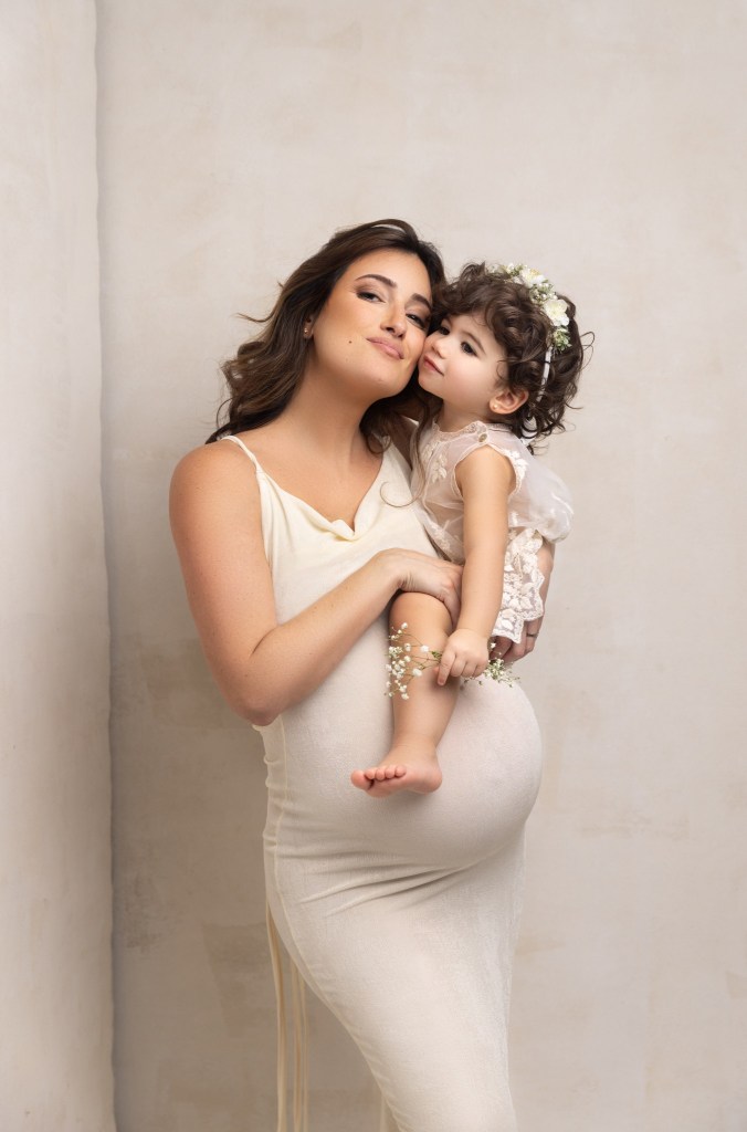 mom and baby girl snuggle her baby bump during a photo session with a nj maternity photographer