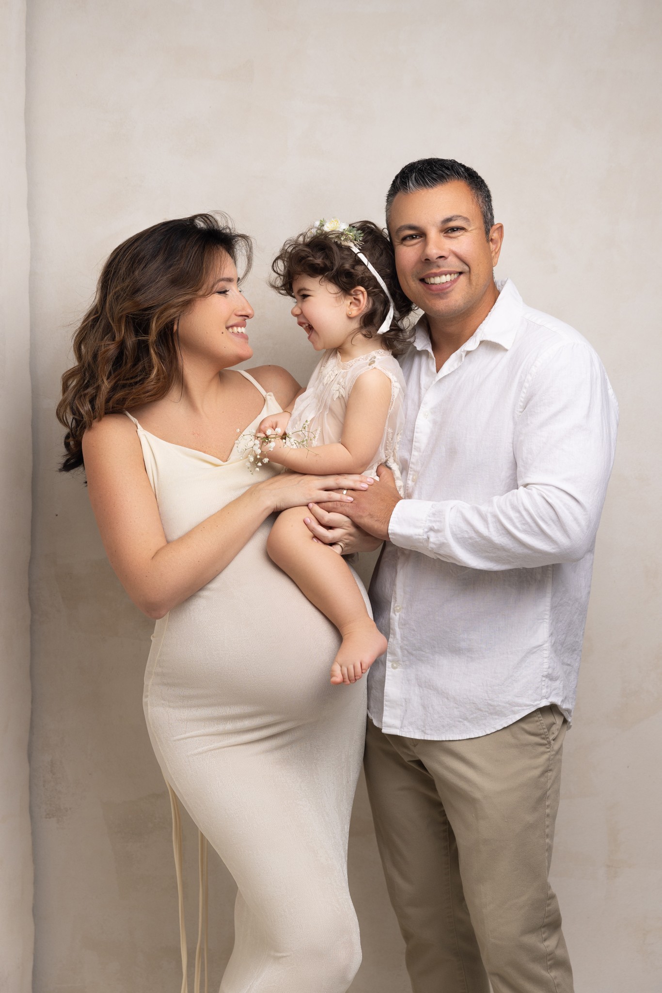 a happy beaming family smile and laugh together during a pose with a nj maternity photographer