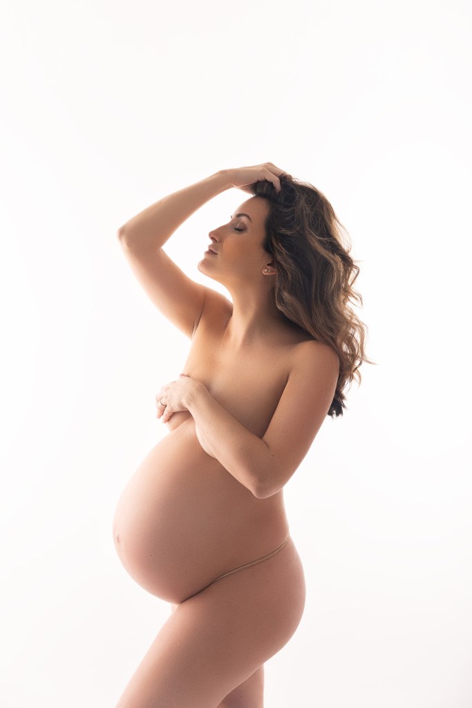 mom's pregnant body is silhouetted in white during a maternity photo session in nj