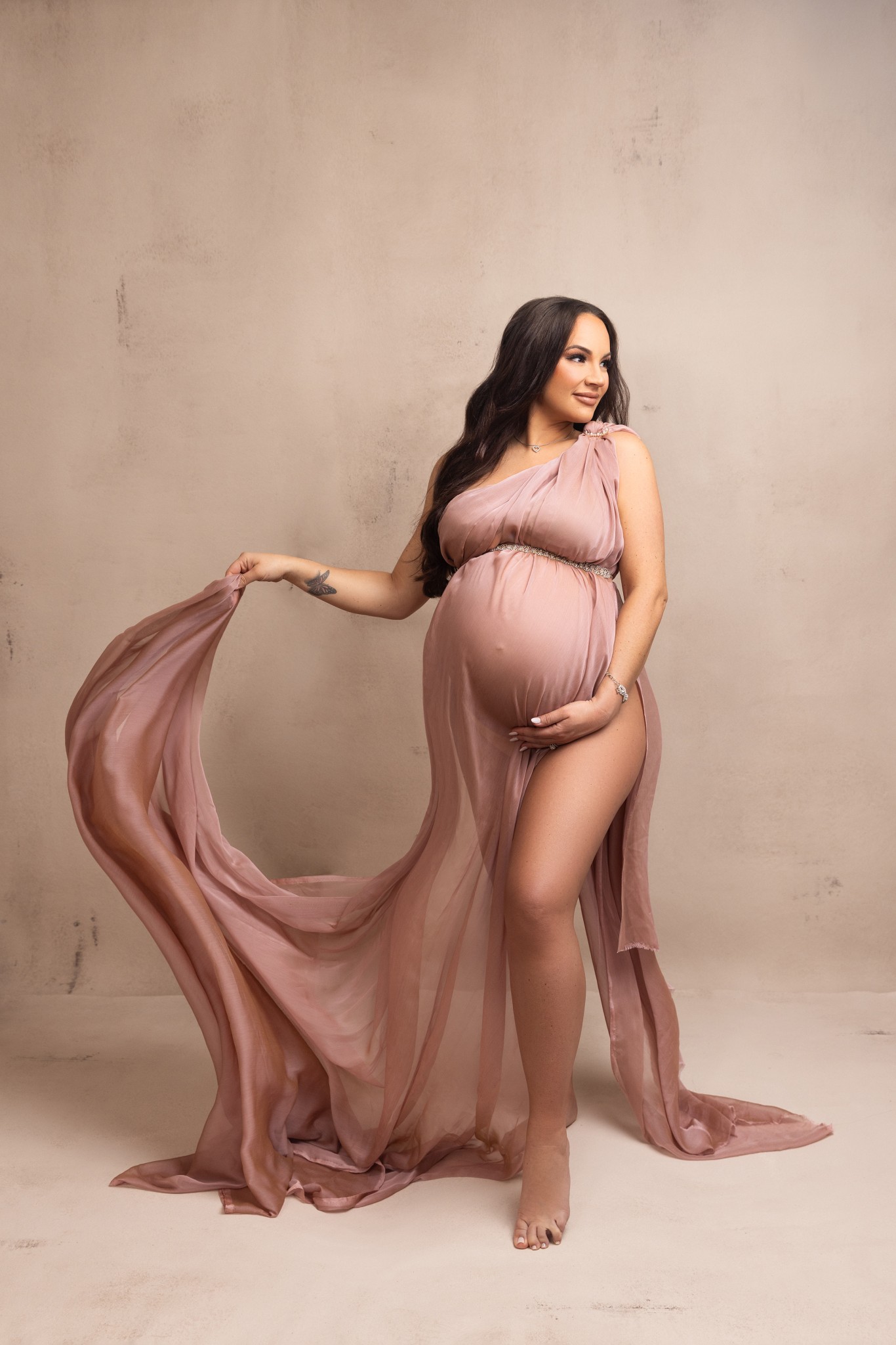 mother to be glows while wrapped in blush pink fabric for her maternity photos with a nj maternity photographer