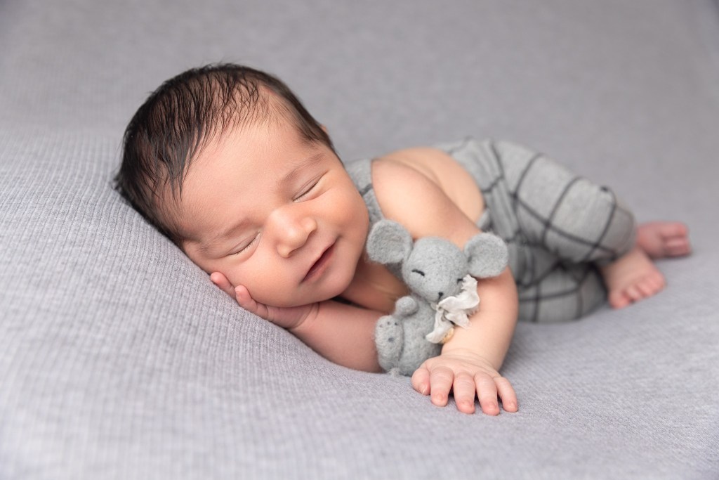 a newborn baby boy smiles for photos during a session with a nj newborn photographer