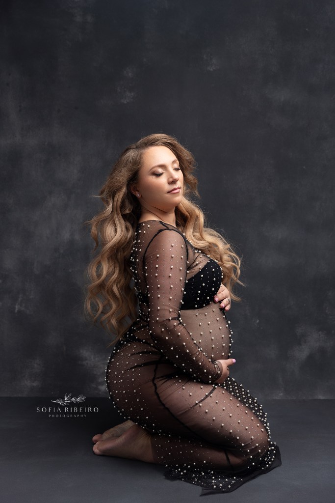 mom poses in a kneeling pose with a beaded sheer black gown