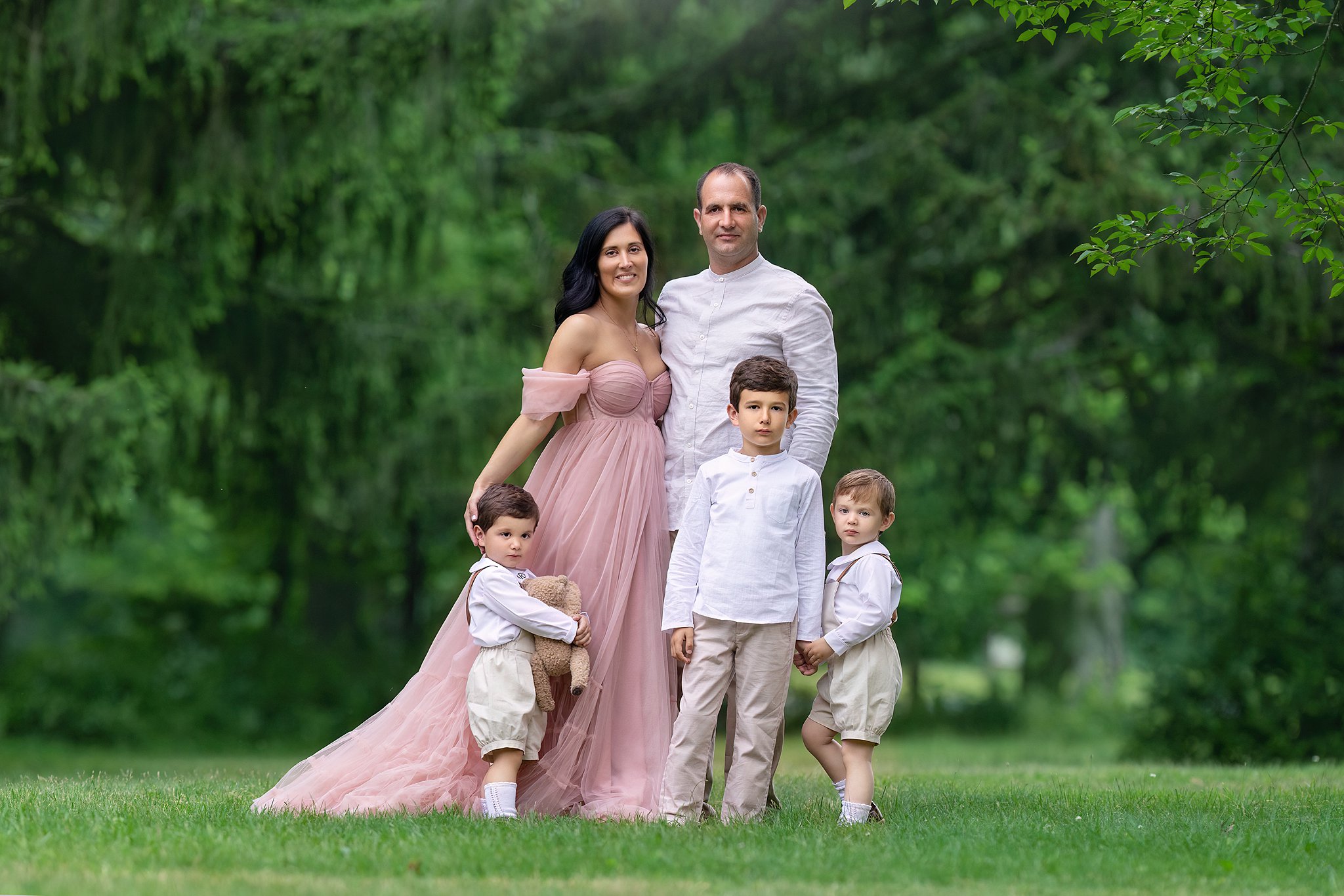 Proud parents stand in a lawn with their three toddler sons after visiting kids birthday party venues nj