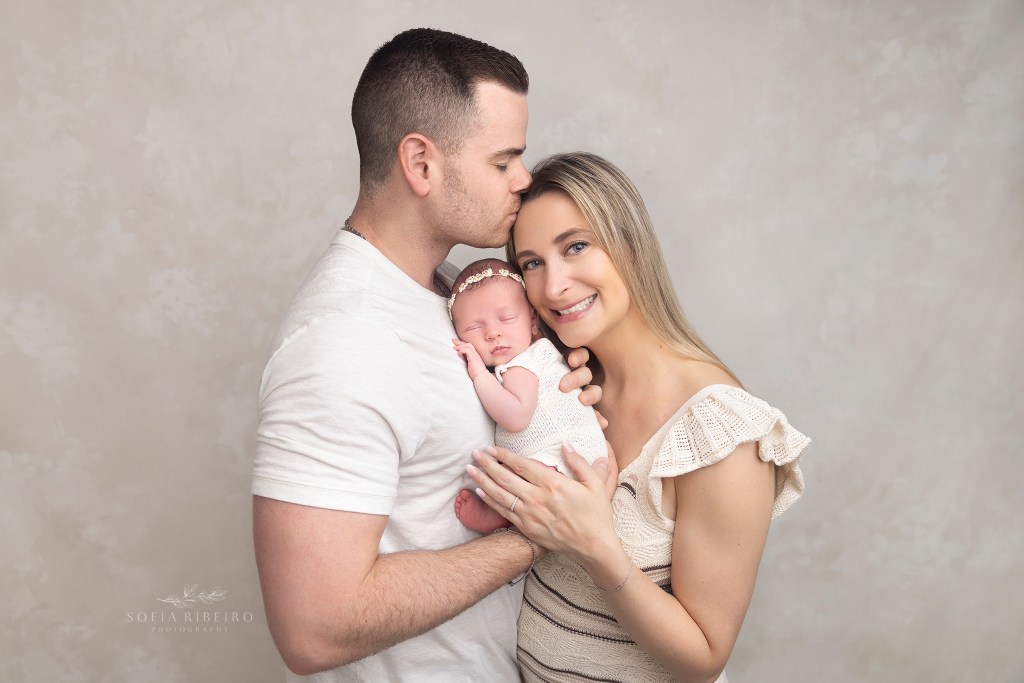dad gives mom a kiss in between newborn photos