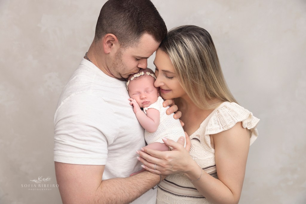 mom and dad snuggle their new baby girl during a portrait session