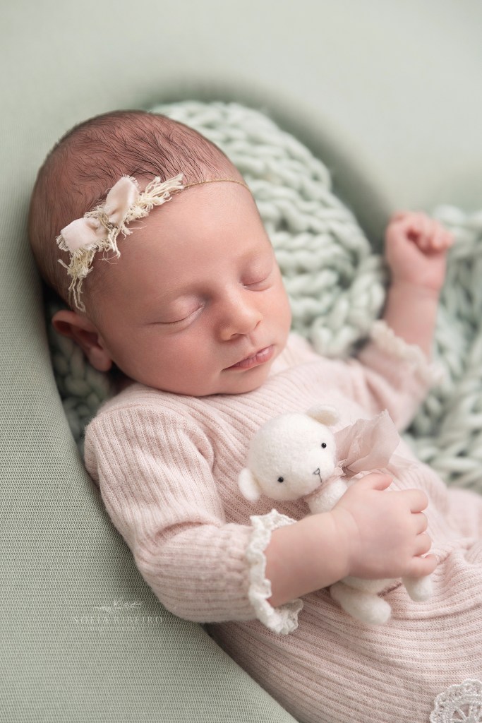 a closeup of a baby girl snuggling a tiny stuffed bear