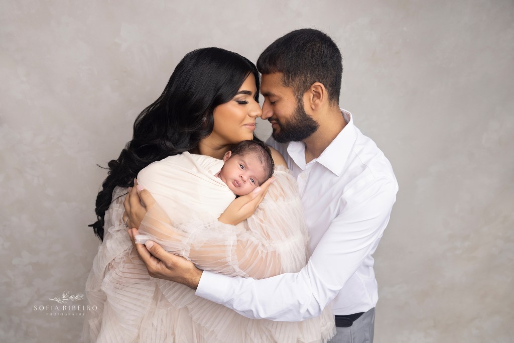 mom and dad lovingly touch noses while holding their newborn baby boy during a photo session in staten island