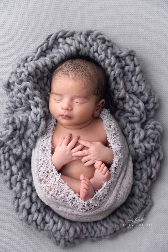 baby boy is swaddled in grey knit fabric, tucked into cozy cable knits for a photo in staten island