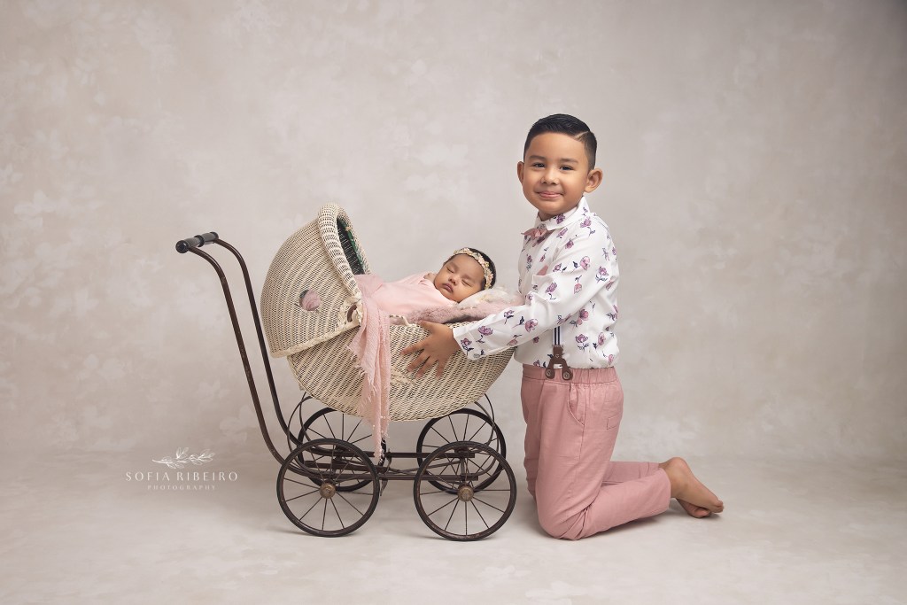 big brother holds baby sister a in a carriage prop during their newborn session in union nj