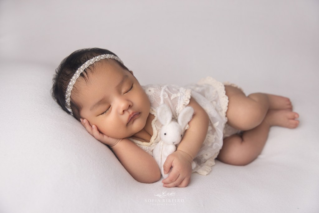 Twin baby girl A sleeps soundly in a white lace outfit during a newborn session in Union NJ
