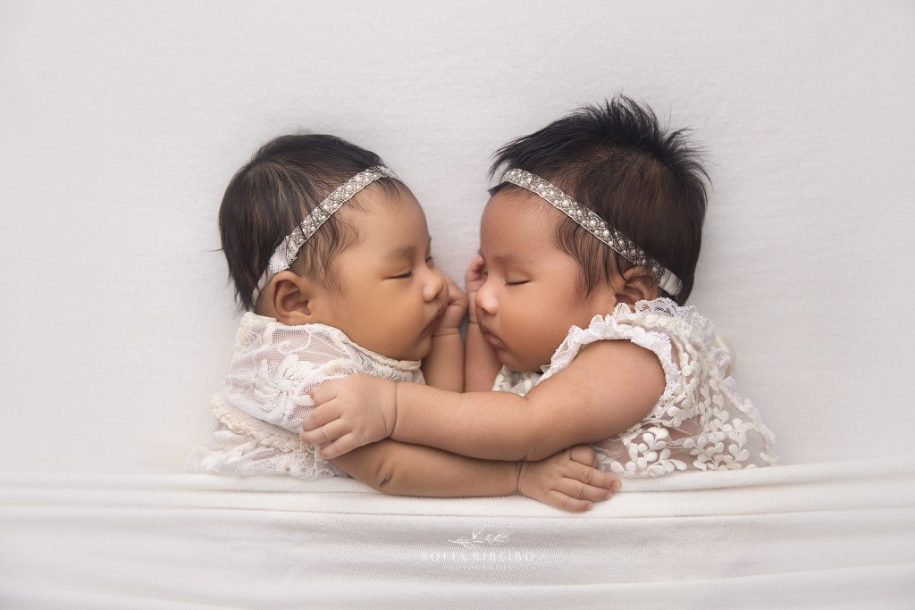 two baby twin sisters snuggle together during their newborn photo session