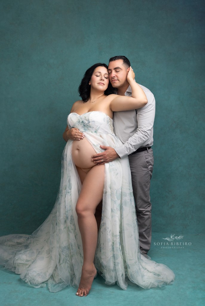 mom and dad snuggle together for a photo showcasing mom's baby bump