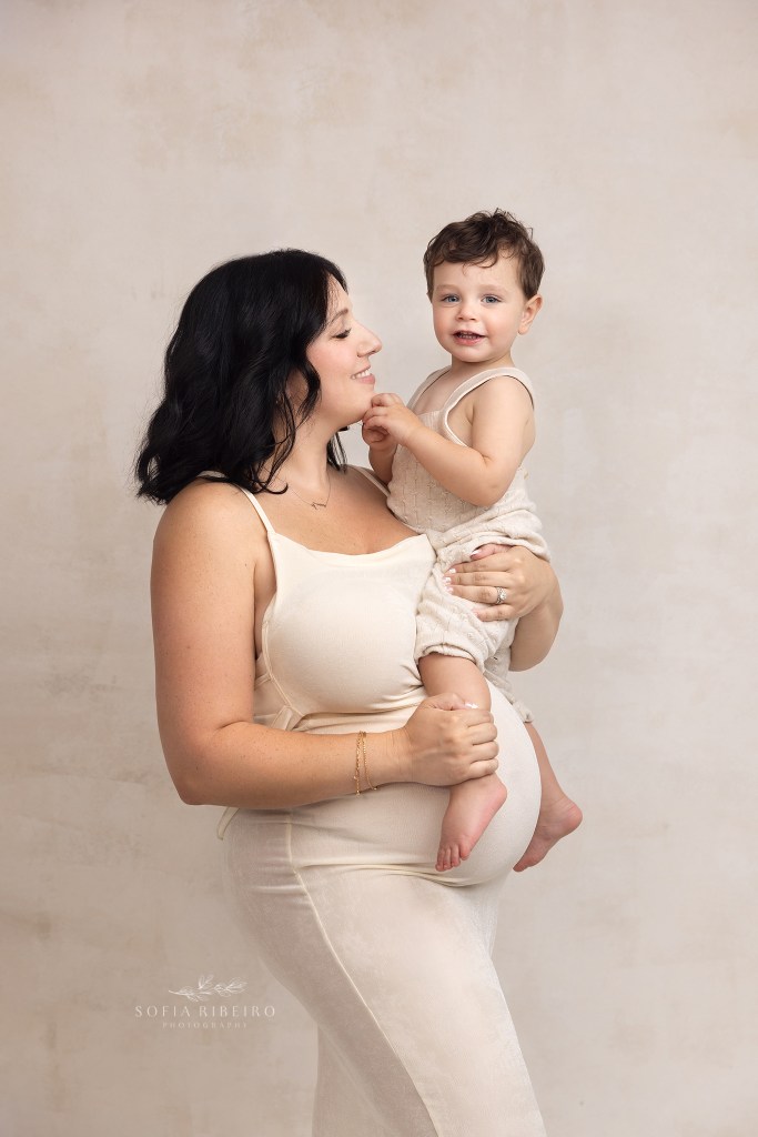 mom cradles big brother over her belly for maternity portraits