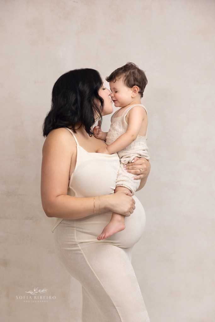 mom cradles big brother over her belly for maternity portraits