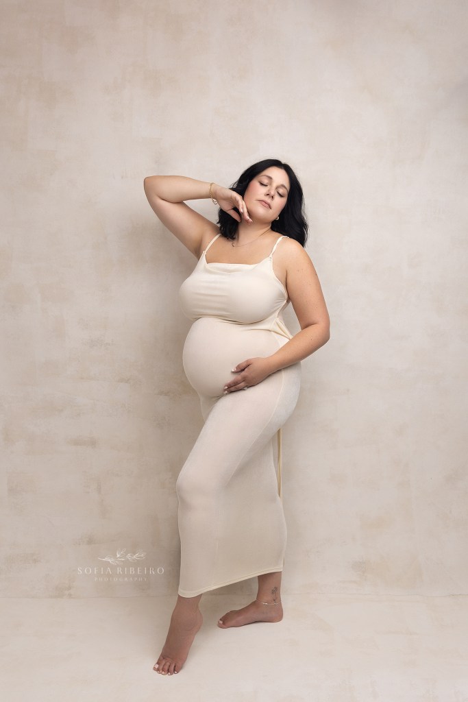 mom poses in a cream dress highlighting her baby bump during a photoshoot with a warren nj maternity photographer