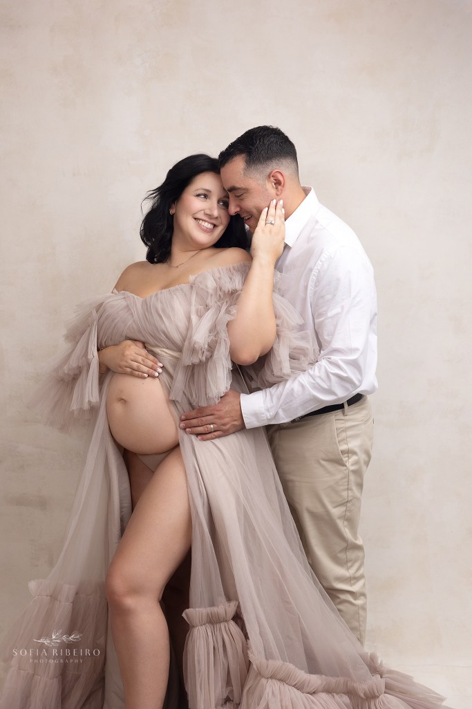 mom and dad snuggle together for a photo during a maternity photo session in warren nj, wearing neutral colors