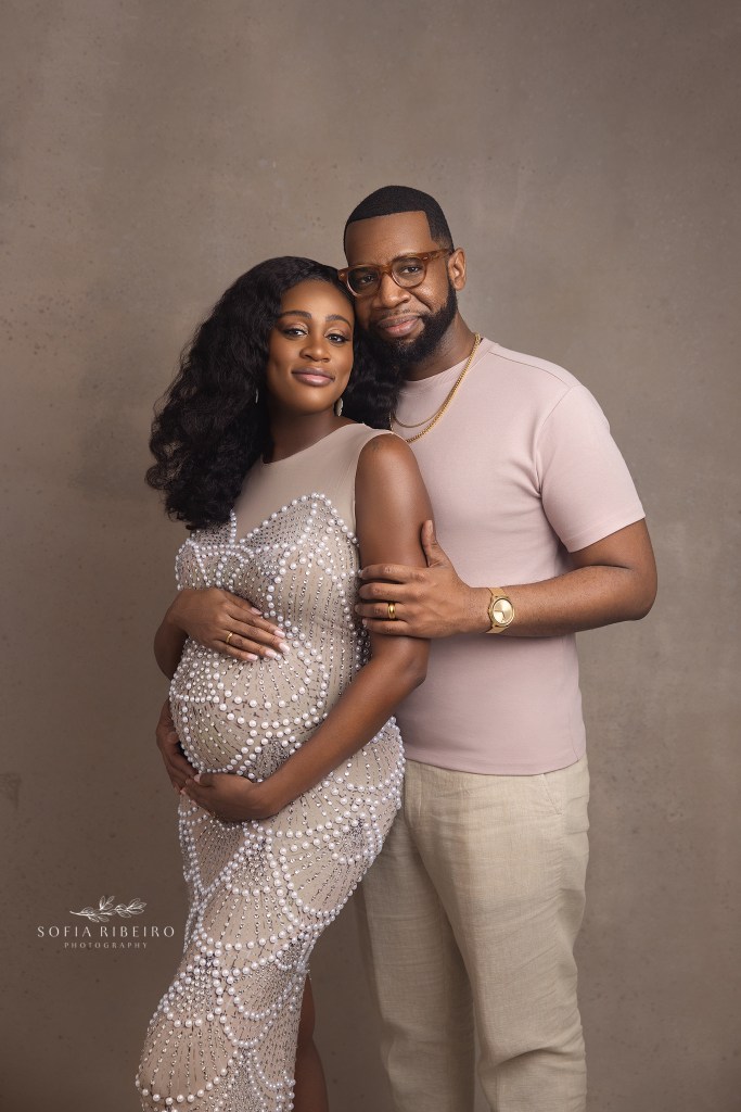 mom and dad smile to camera in neutral looks during their maternity photos in west orange nj