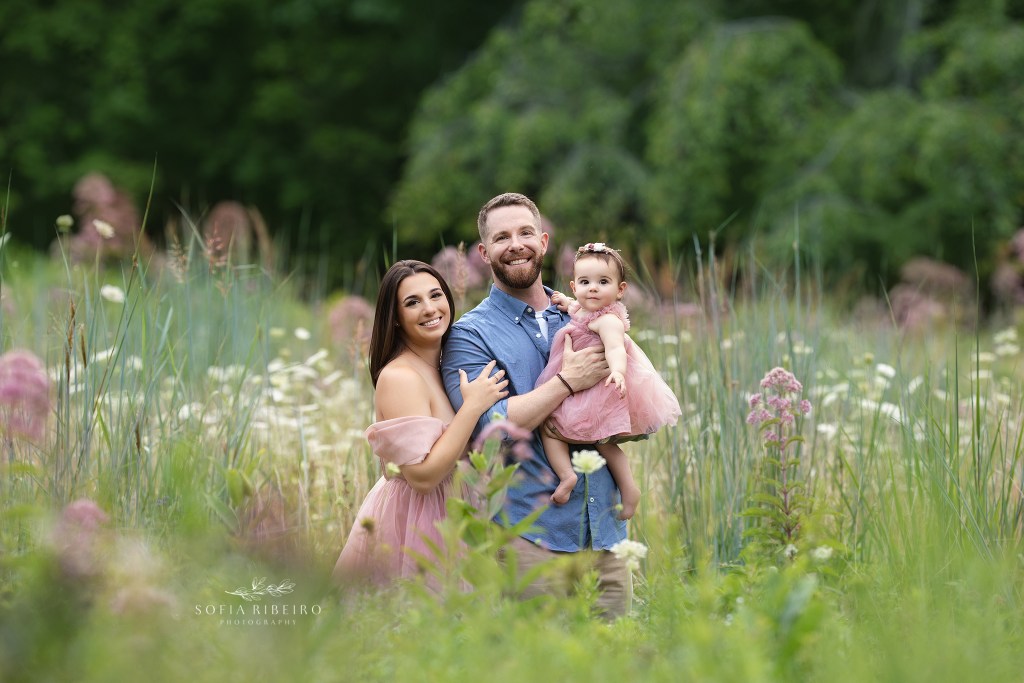 mom, dad, and baby girl are all smiles for this sweet portrait in an afternoon field of flowers in westfield nj