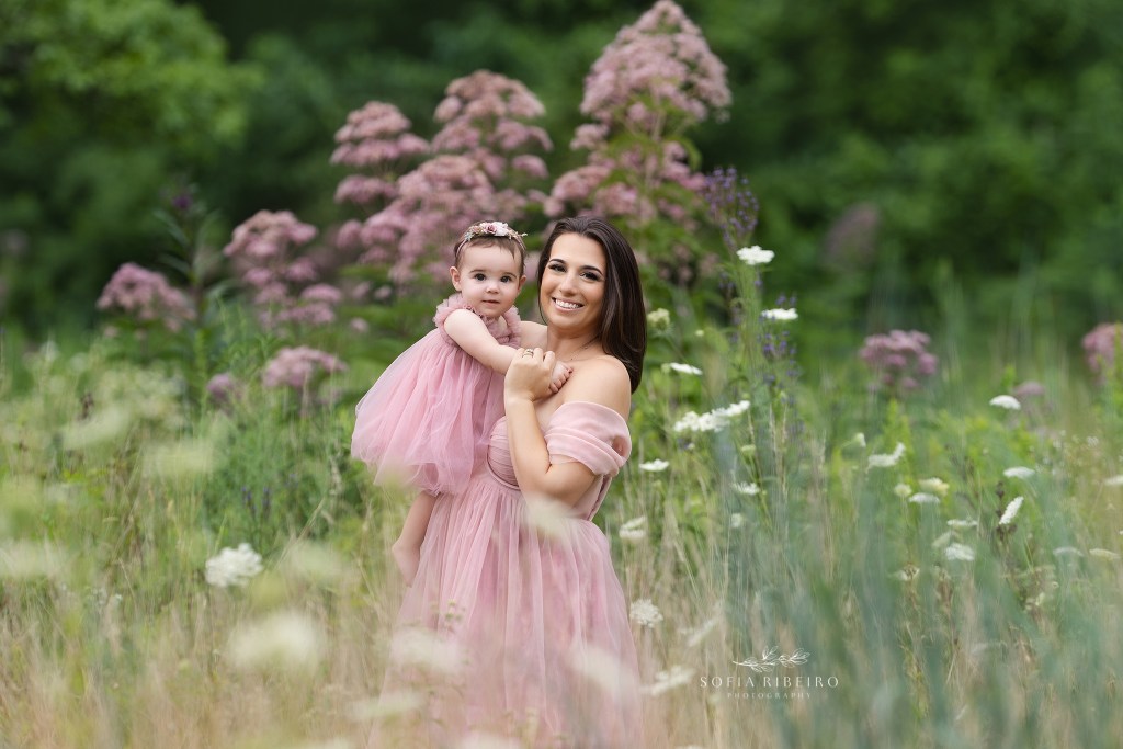mom and baby girl snuggle for a sweet photo in a pink field of flowers in westfield nj