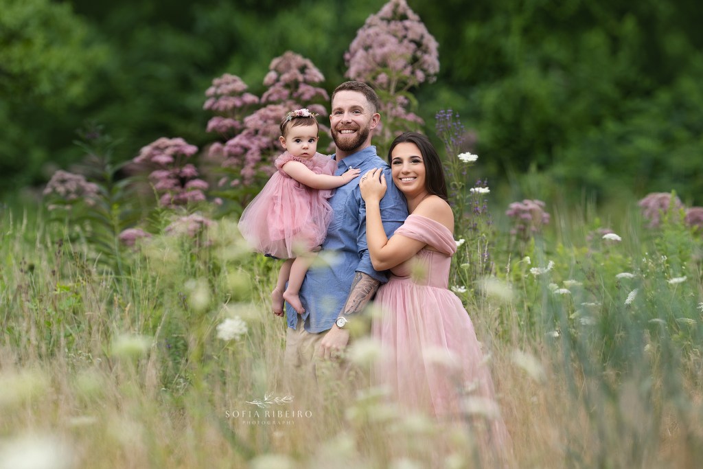 a westfield nj family photographer captures a family of three in a sweet embrace in the middle of a delicate wildflower field
