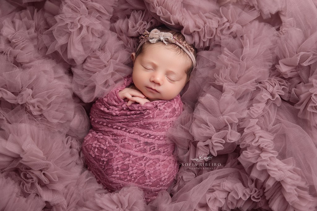 baby sleeps soundly in pink tulle for newborn photos