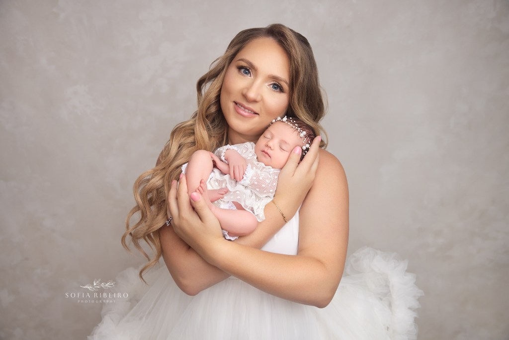 mom poses, sweetly smiling at the camer with her new baby girl