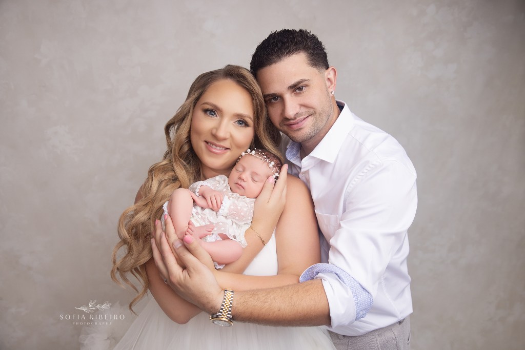 mom and dad pose proudly in neutrals for baby girl's newborn session photos