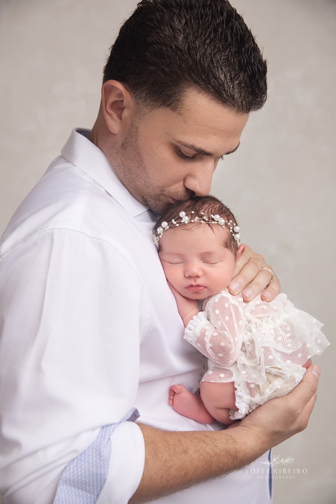 dad gives baby girl a kiss during newborn photos