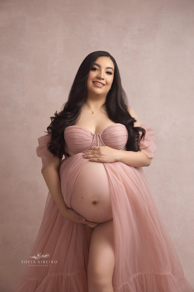 mom smiles to camera, holding her belly