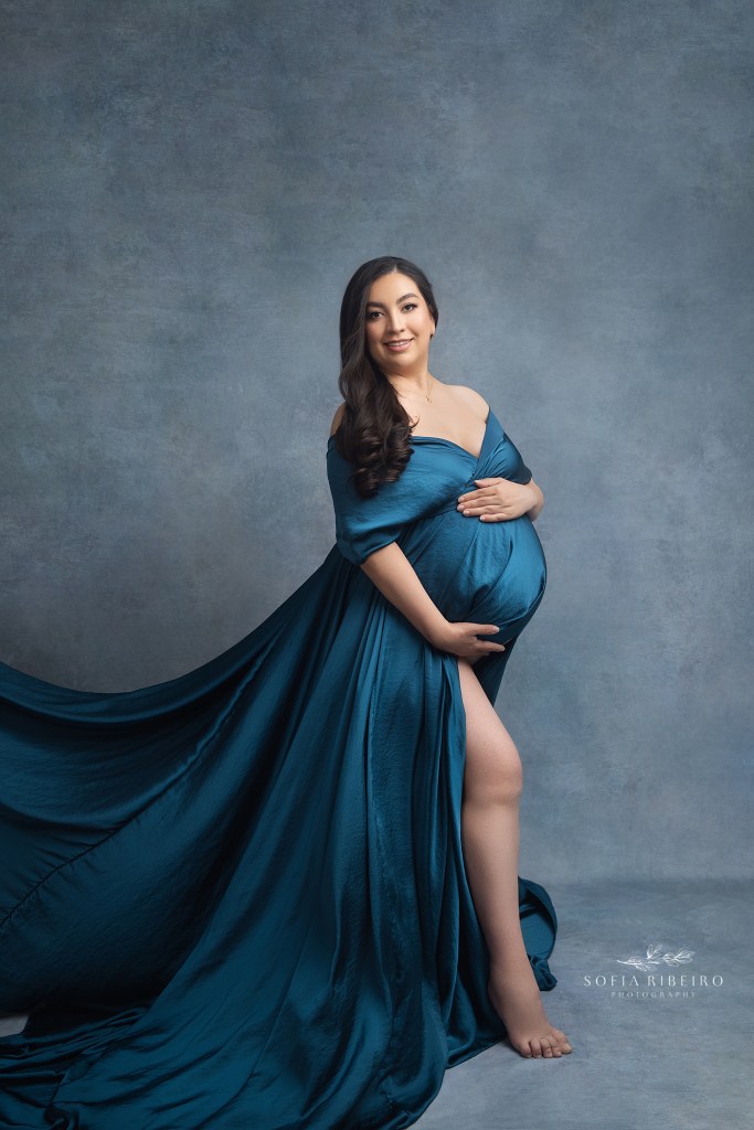 mom is draped in a gorgeous flowing blue fabric by maternity photography studio in hackensack nj