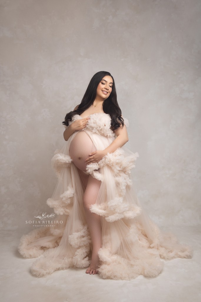 hackensack nj maternity photograpner captures a glowing mom wearing a cream ruffled dress in a moment of serenity