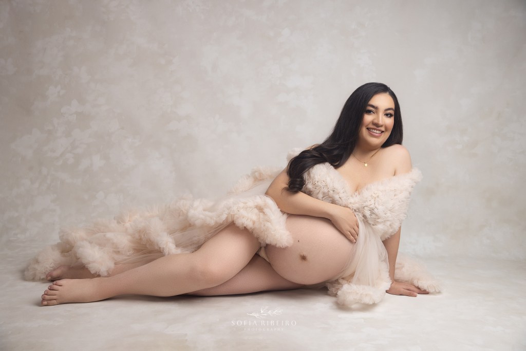 mom is a dream in a ruffled cream gown with her hand gently resting on her belly for a maternity photo in hackensack nj