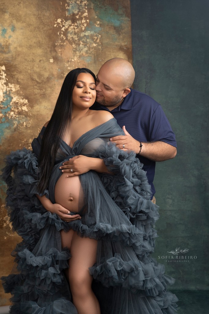 dad gives mom a sweet kiss during their maternity portraits