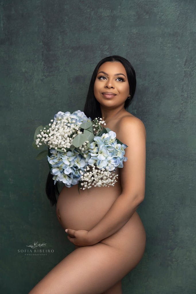 mom holds a bouquet of flowers over her belly during a maternity photo session in hudson ny