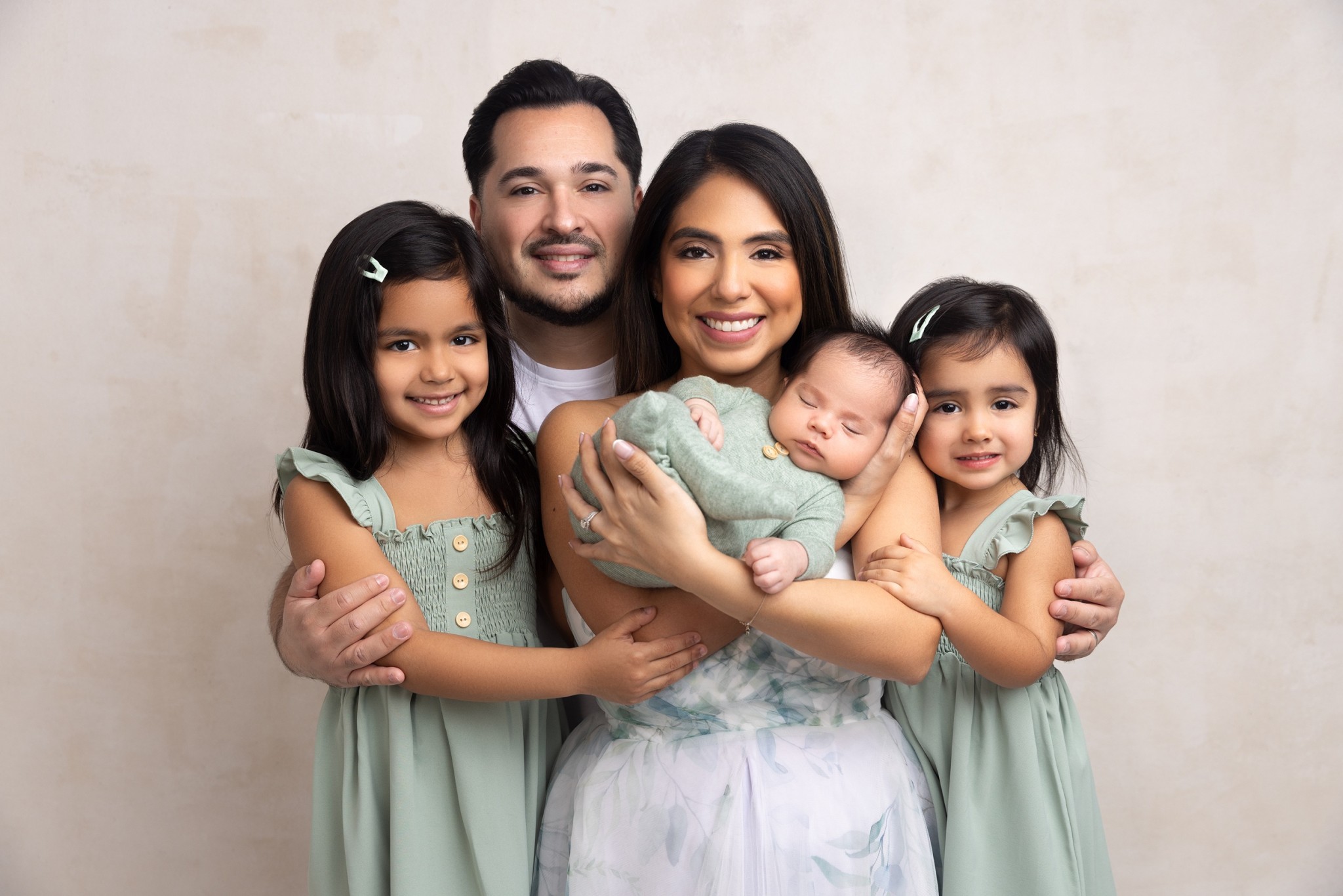 A happy family of 5 hug and smile while in a studio after visiting madison nj pediatricians