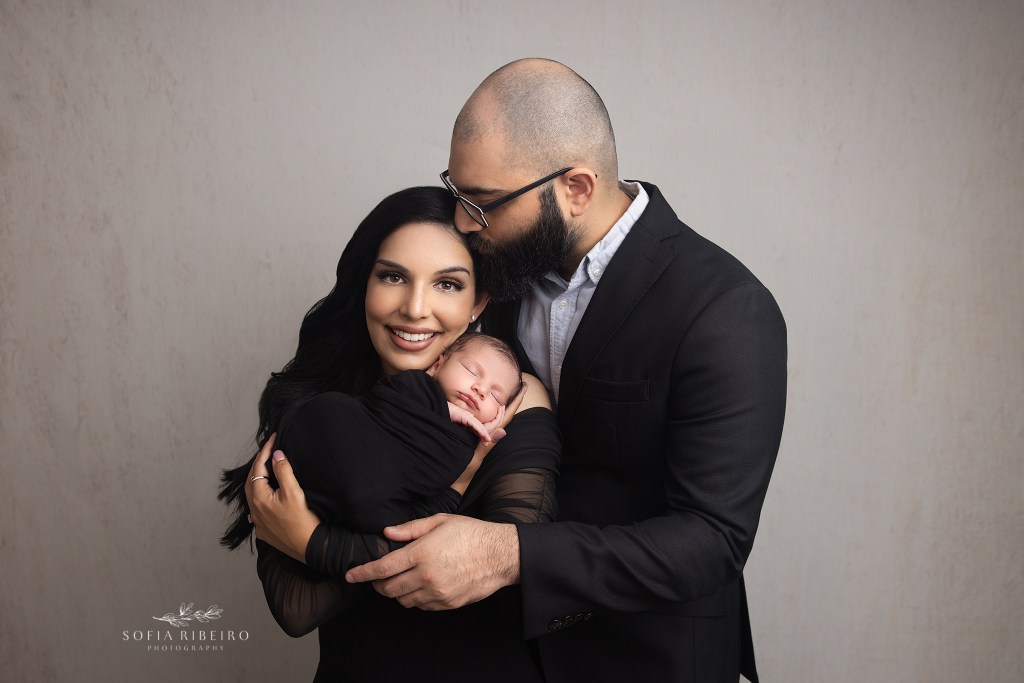 dad and mom snuggle together with a new baby during a photo session with a pennsylvania newborn photographer