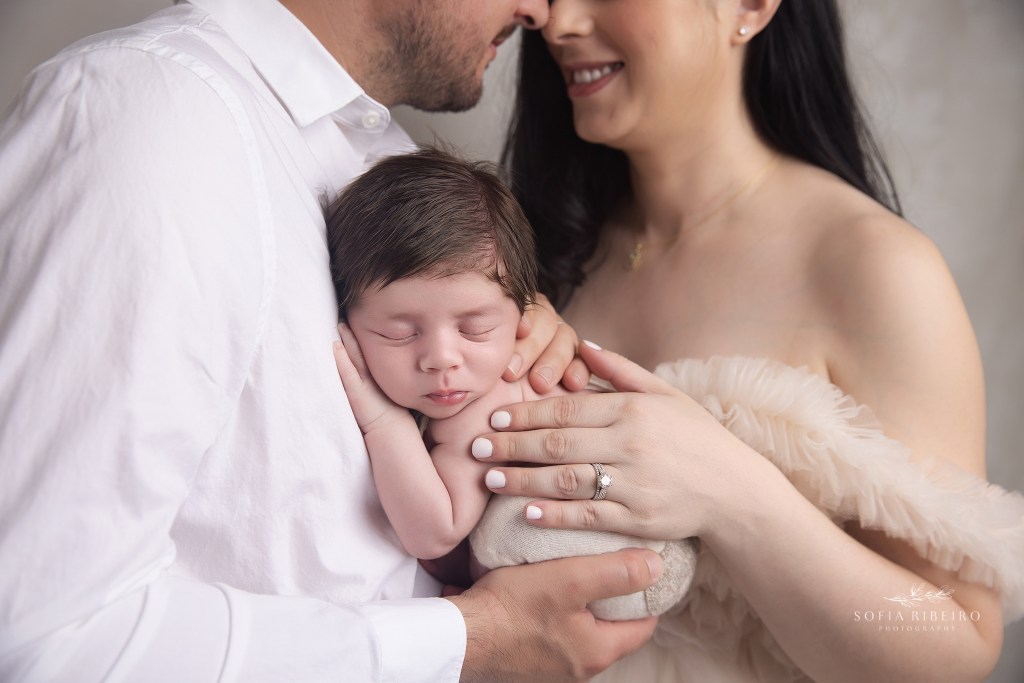 baby boy is posed sweetly in parents hands for a closeup during newborn photos