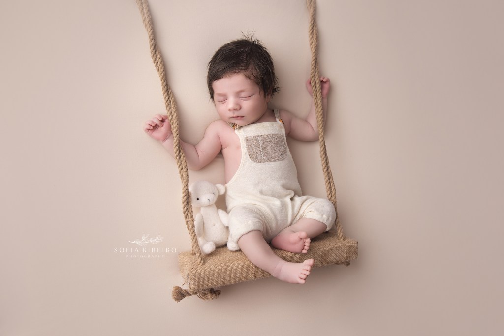 a newborn baby boy is posed on a swing prop during photos in south amboy nj
