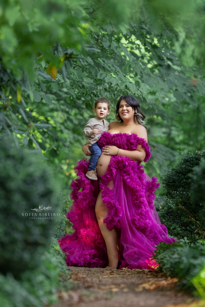 mom poses with her older baby for a portrait with her belly exposed