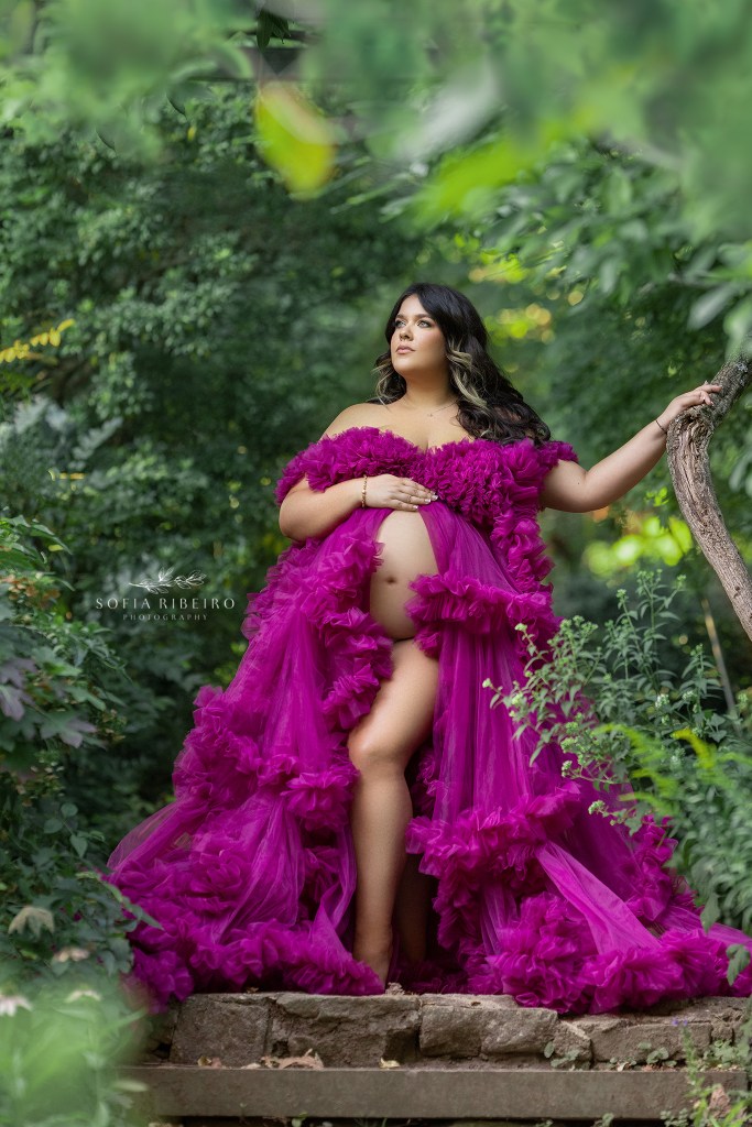 mom to be poses in a regal magenta ruffled gown for a maternity portrait in scenic greenery in janover nj