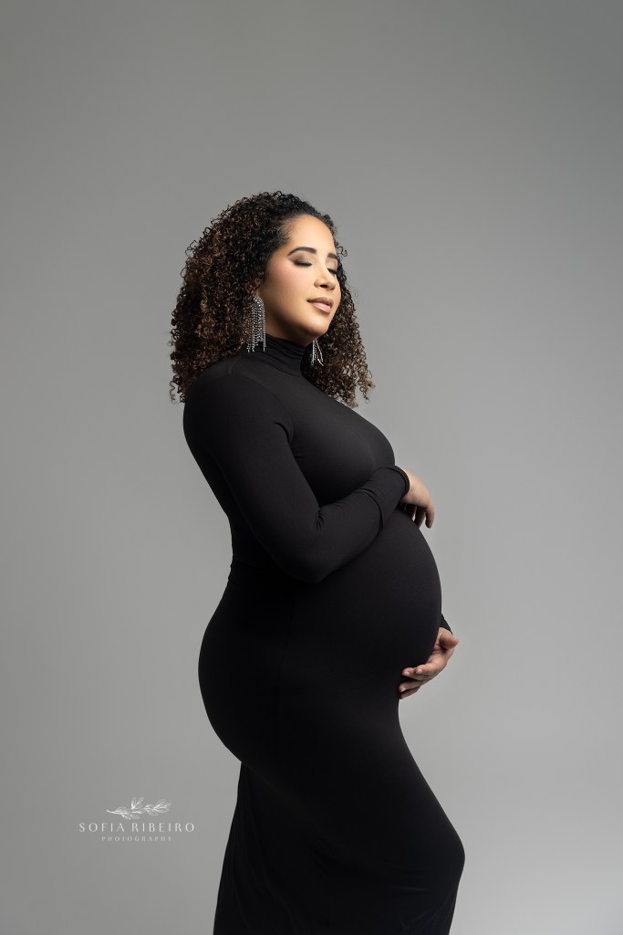 mom is a picture of elegance, posing with eyes closed while cradling her baby bump in a skin tight black dress for saddle river nj maternity photographer sofia ribeiro
