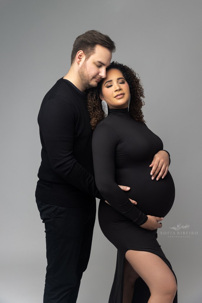 mom and dad share a sweet cuddle while cradling moms baby bump for a portrait