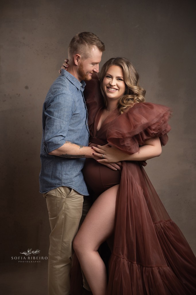 mom and dad share a giggle while posing for a maternity portrait