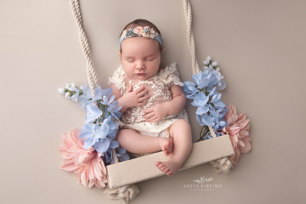 baby girl sleeping sweetly on a swing prop adorned with florals